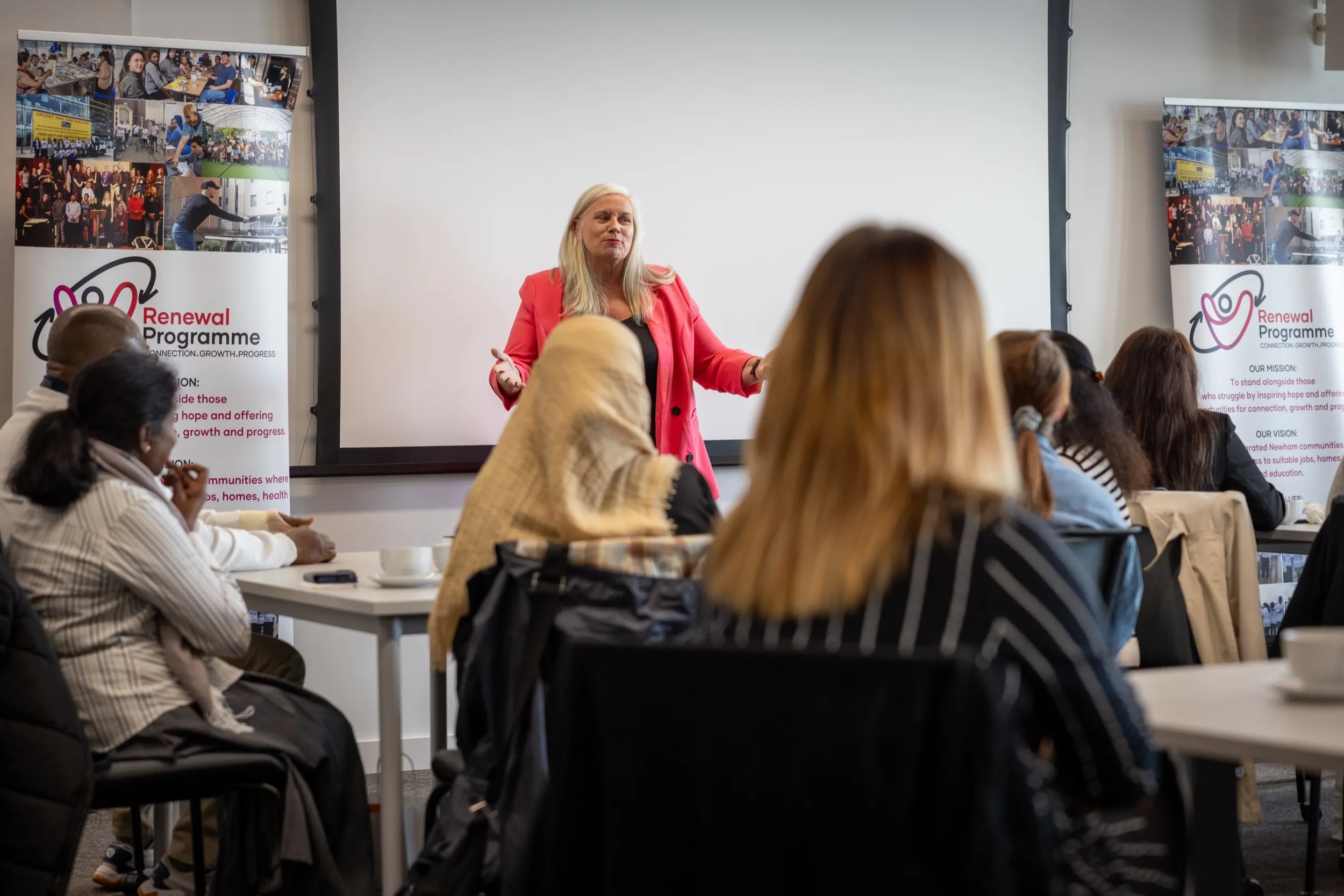 Dr Alison Edgar MBE leading a workshop, speaking to a room of participants at their tables.