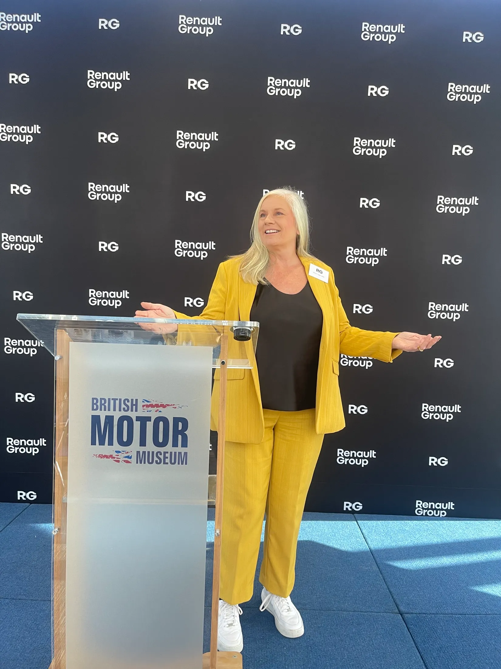 Alison at the British Motor Museum podium, arms out, against the Renault Group backdrop.